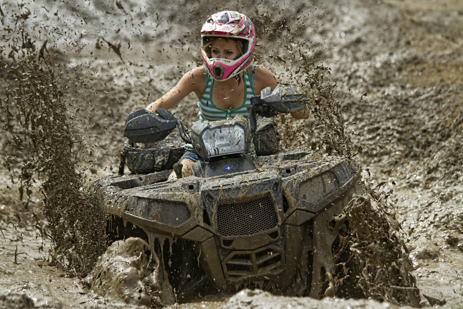 A rider powering an ATV through rugged off-road terrain